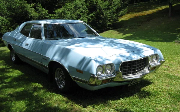 A sleek Ford Gran Torino parked on lush green grass, displayed in vibrant detail, serves as a stunning HD desktop wallpaper and background.