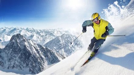 HD desktop wallpaper showing a skier in bright gear descending a snowy mountain slope with rugged peaks in the background, capturing the thrill of winter sports.