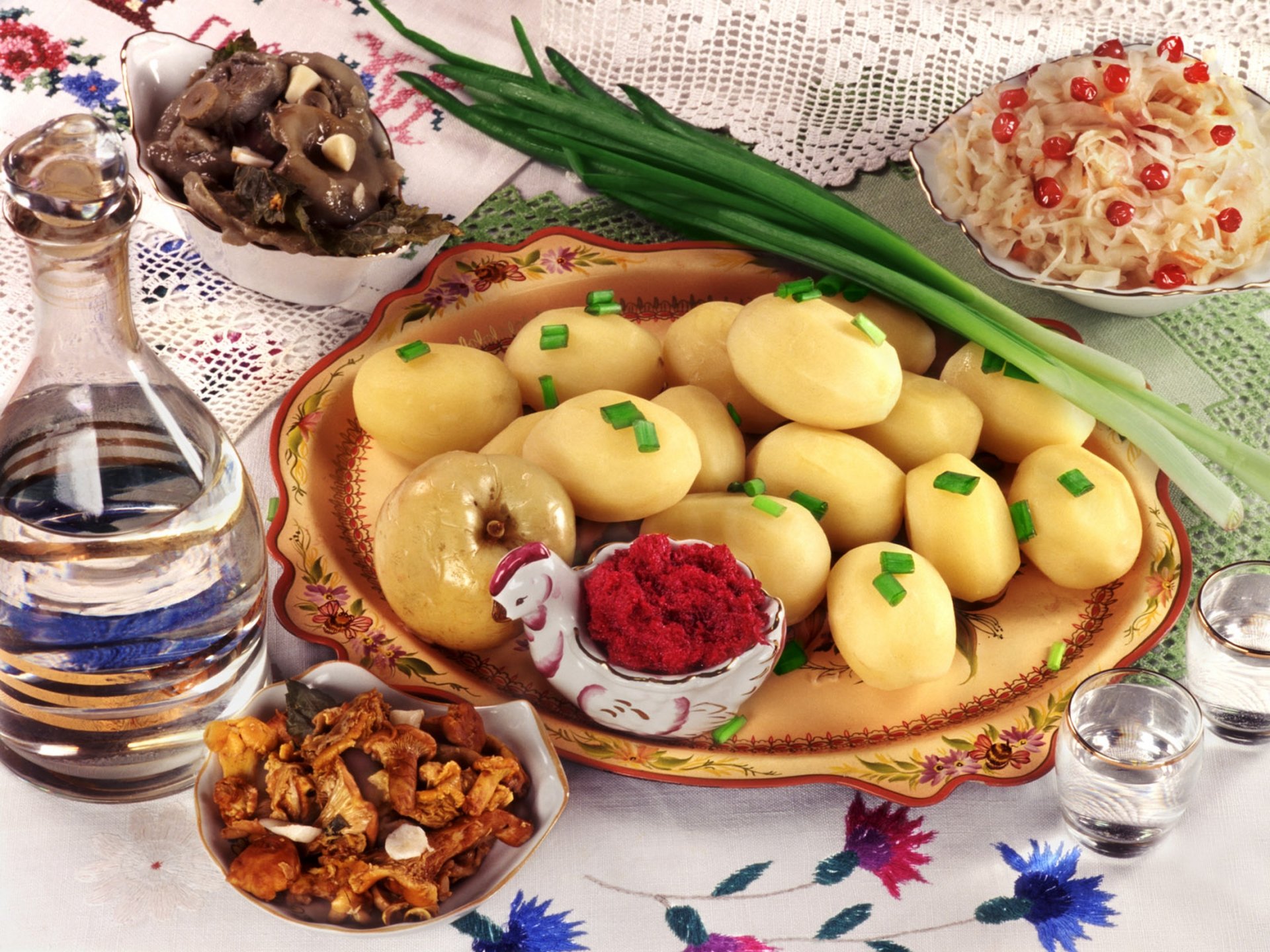 HD PC desktop wallpaper featuring a plate of boiled potatoes garnished with green onions, surrounded by various traditional side dishes and condiments.