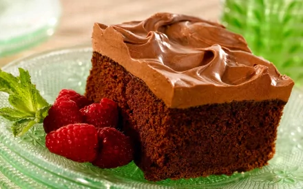 Slice of chocolate cake with smooth chocolate icing, raspberries and mint on a plate — sweets food dessert; 2K Quad HD PC desktop wallpaper background.