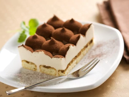 HD PC desktop wallpaper featuring a close-up of a creamy tiramisu dessert dusted with cocoa powder on a white plate with a fork.