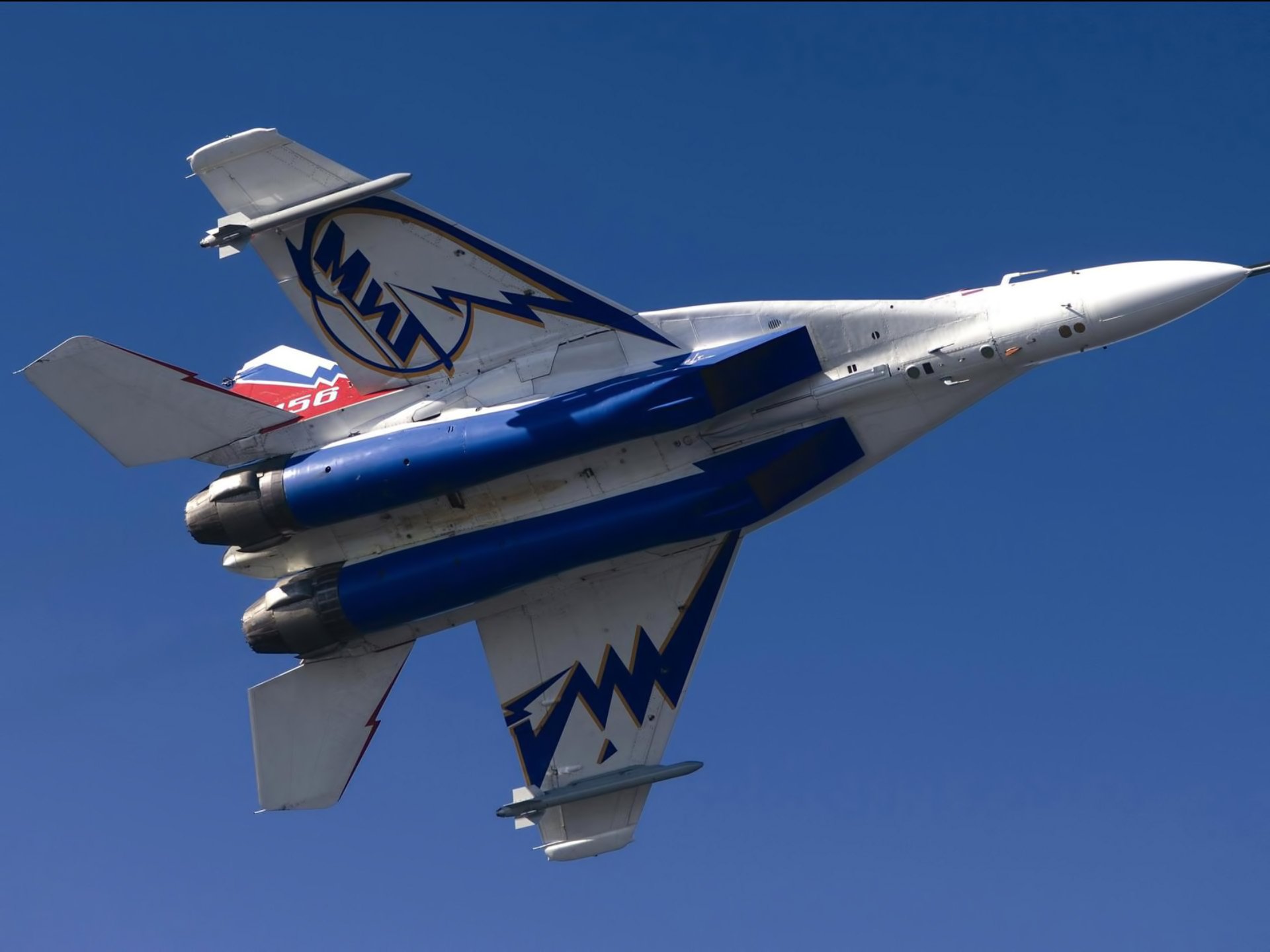 HD PC desktop wallpaper featuring a Mikoyan MiG-29 military jet soaring against a clear blue sky.