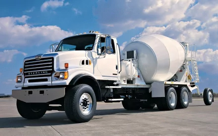 A white cement mixer truck stands prominently against a blue sky with fluffy clouds, showcased as a high-definition PC desktop wallpaper and background.