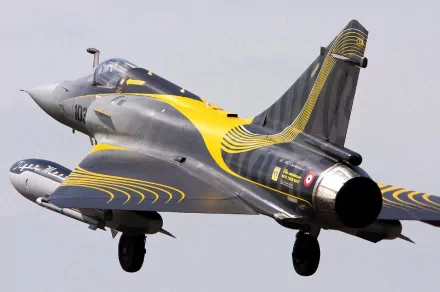 HD desktop wallpaper featuring a military Dassault Mirage 2000 fighter jet in flight with black and yellow accent markings.