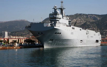 HD desktop wallpaper of the French Navy amphibious assault ship Mistral (L9013), a helicopter carrier warship docked at port with mountainous background.