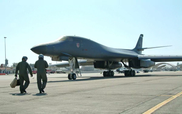 HD desktop wallpaper featuring a Rockwell B-1 Lancer military bomber on the runway with two crew members walking nearby.