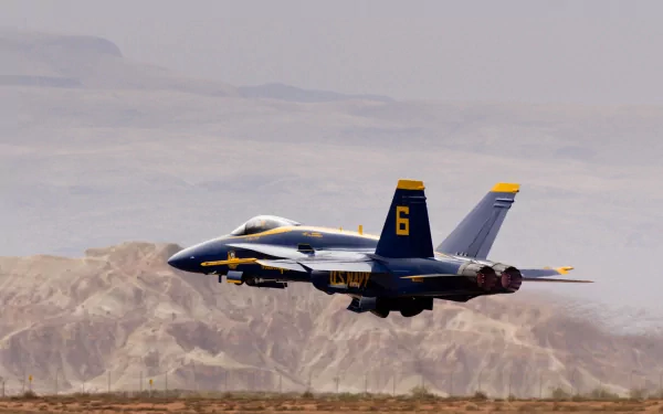 HD PC desktop wallpaper background: blue-and-yellow military fighter jet numbered 6 making a low pass over a desert landscape at an air show.
