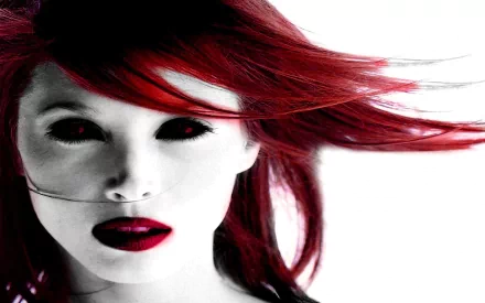 A striking HD wallpaper featuring a gothic, dark aesthetic. The image showcases a woman with vibrant red hair and dramatic makeup, creating an intense and captivating look.