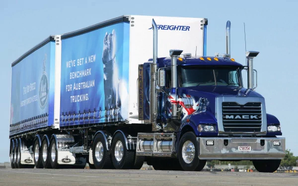 HD desktop wallpaper featuring a blue Mack Trucks big rig semi parked on a clear day, showcasing the vehicle's powerful design and detailed trailer artwork.