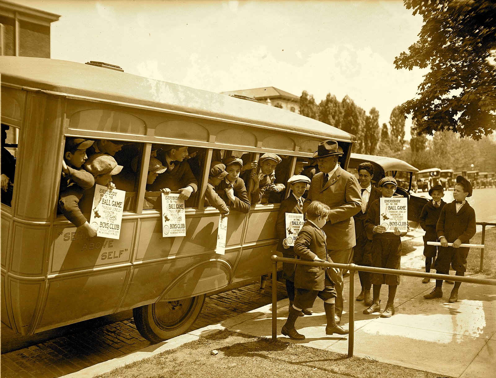 Sepia HD PC Desktop Wallpaper and Background of a vintage vehicle bus: crowded early-20th-century bus with conductor assisting passengers at a roadside stop beneath trees.