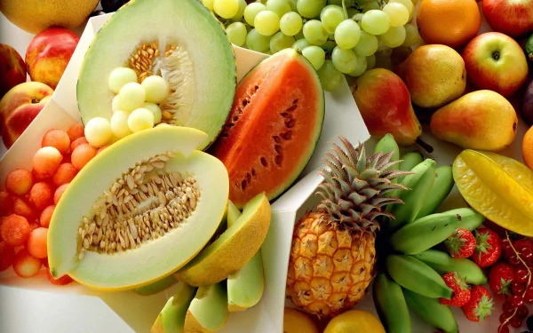 HD PC desktop wallpaper featuring a colorful assortment of fresh fruits including pear, banana, pineapple, honeydew, grapes, and watermelon.