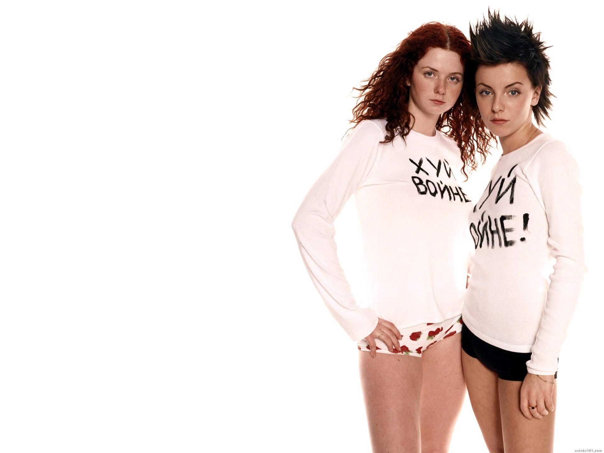 HD PC desktop wallpaper of a female music duo: two women in white graphic tees and shorts posing against a bright white background, minimalist pop aesthetic.