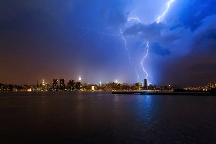 HD PC desktop wallpaper capturing a dramatic lightning bolt striking over a city skyline at night, with reflections shimmering on the water.