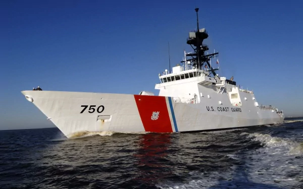 A U.S. Coast Guard cutter in action, cutting through the waves under a clear blue sky, showcasing the strength and presence of military maritime operations. HD desktop wallpaper.