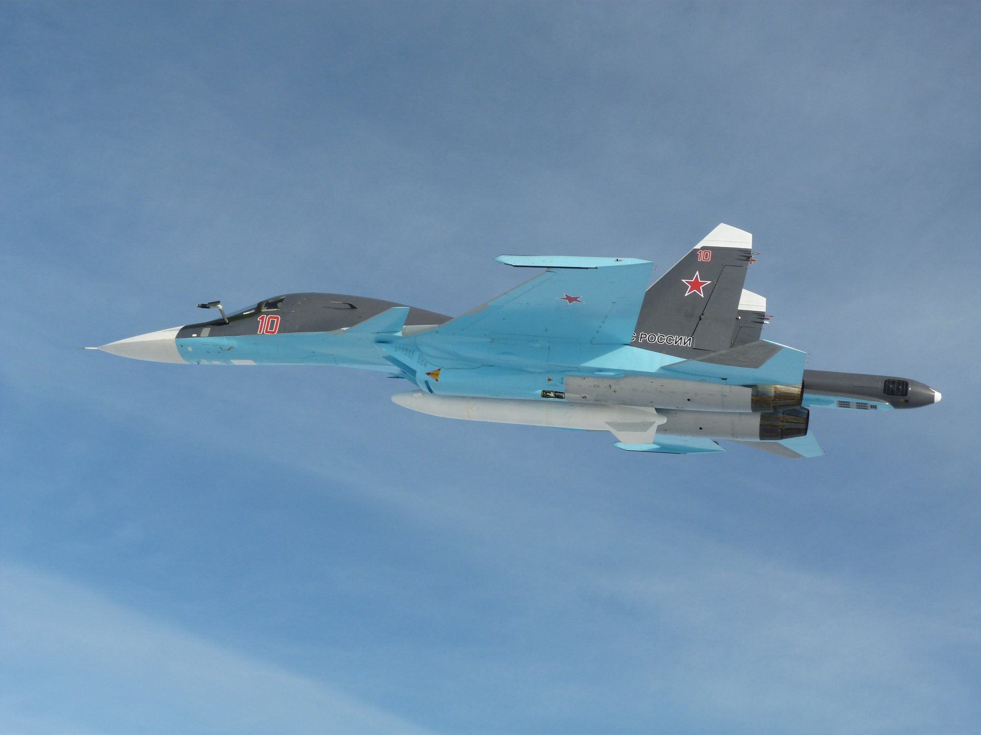 4K Ultra HD PC desktop wallpaper: blue-green Russian Sukhoi Su-34 military fighter-bomber cruising against a pale blue sky.