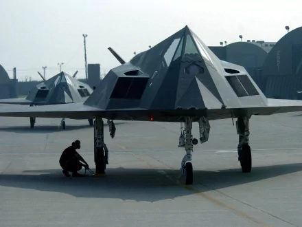 HD desktop wallpaper featuring Lockheed F-117 Nighthawk stealth aircraft on the tarmac, with a United States Air Force personnel working near one of the planes.