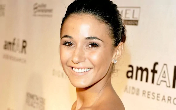 I don't know who this person is. Alt: Smiling woman with pulled-back hair at an event against a beige backdrop; warm close-up, 2K Quad HD desktop wallpaper.