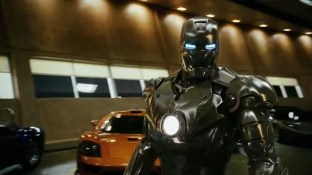HD desktop wallpaper featuring Tony Stark as Iron Man, with glowing blue eyes and chest reactor, standing in front of an orange sports car inside a dimly lit garage.