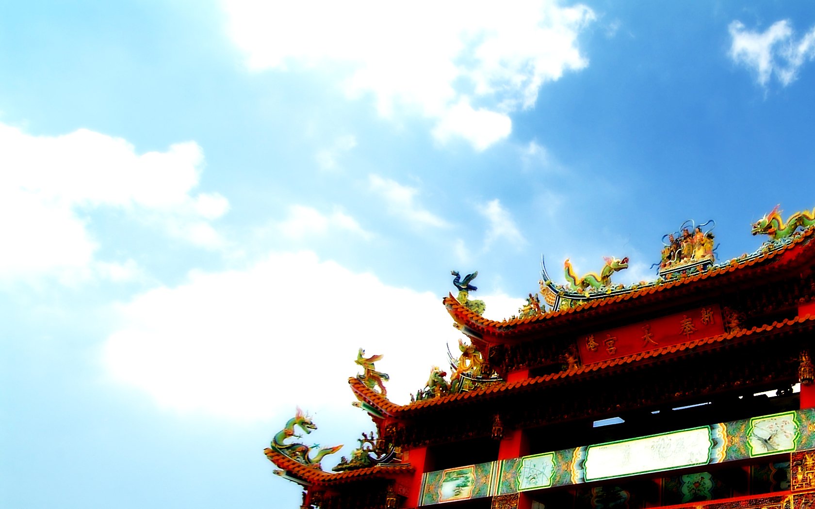 A vibrant temple rooftop adorned with intricate sculptures contrasts against a bright blue sky, creating a stunning HD desktop wallpaper and background.