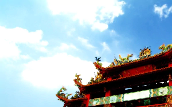 A vibrant temple rooftop adorned with intricate sculptures contrasts against a bright blue sky, creating a stunning HD desktop wallpaper and background.