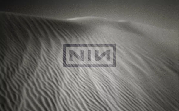 An HD desktop wallpaper featuring abstract sand dunes, overlaid with the Nine Inch Nails logo, creating a striking visual for music fans.