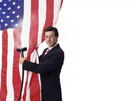 Stephen Colbert poses playfully with an American flag in this vibrant 4K Ultra HD wallpaper from The Colbert Report, showcasing his signature blend of humor and patriotism.