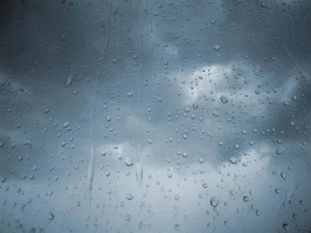 HD desktop wallpaper featuring photography of water drops on a window with a cloudy sky background.