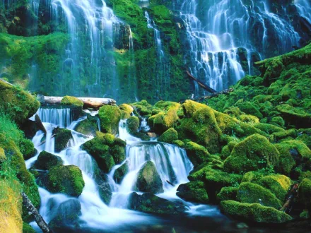 HD desktop wallpaper of a serene nature scene featuring a lush green landscape with a cascading waterfall flowing over moss-covered rocks.