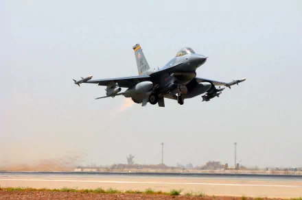 HD desktop wallpaper of a General Dynamics F-16 Fighting Falcon taking off from a military airbase, showcasing the aircraft in flight with clear skies in the background.
