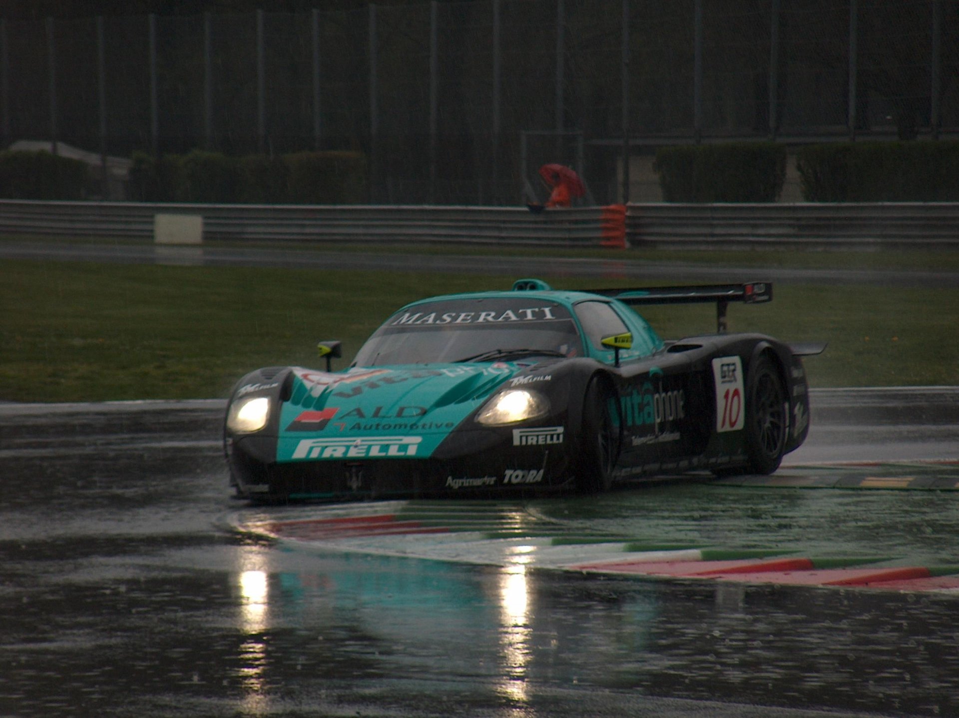 A Maserati racing vehicle navigates a wet track, showcasing its dynamic design and performance, captured in an HD PC desktop wallpaper.