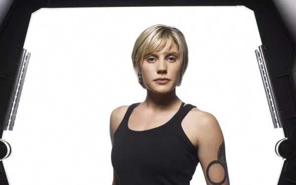 Kara Thrace from the TV show Battlestar Galactica (2003) poses confidently against a bright background, showcasing her iconic look in this HD desktop wallpaper.