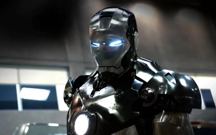 HD desktop wallpaper featuring Iron Man in his iconic metal suit with glowing eyes and chest, standing in a dimly lit setting.