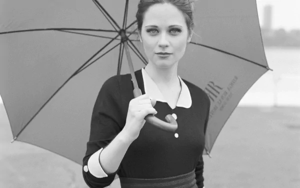 A stylish black and white HD wallpaper featuring Zooey Deschanel holding an umbrella, exuding a confident and captivating presence.