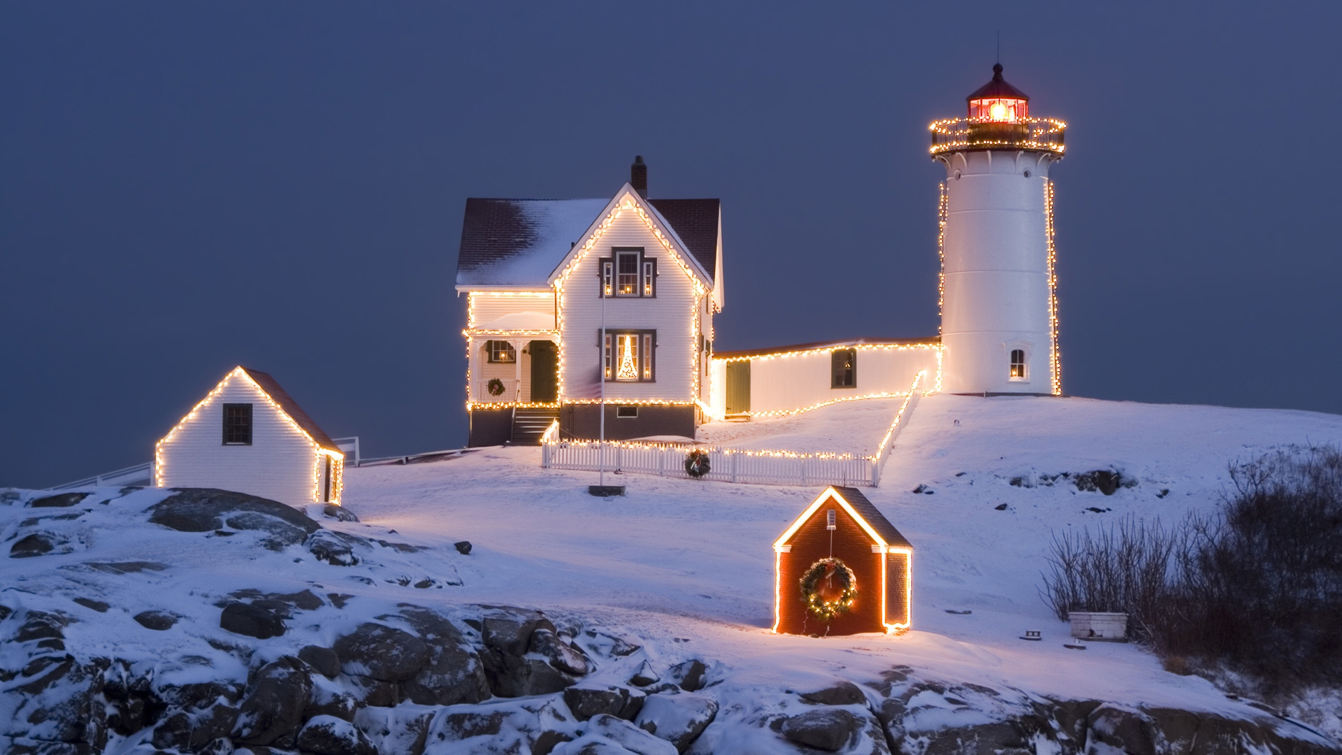 Winter scene with a lighthouse amid snow and Christmas lights