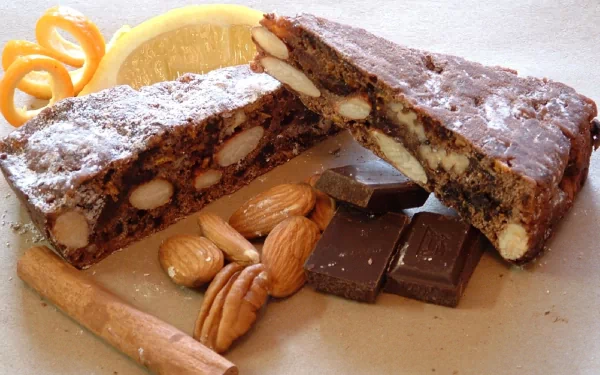 A delicious assortment of sweets featuring a split chocolate bar with nuts, surrounded by almonds, pecans, and a slice of lemon, captured as a HD PC desktop wallpaper.