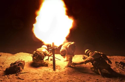 HD wallpaper showing soldiers operating a mortar at night, with a bright explosion illuminating the scene. The image captures the intensity and dynamic nature of military action.