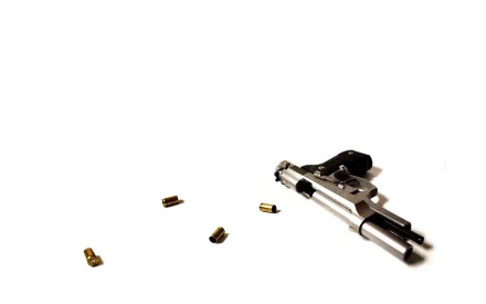 HD desktop wallpaper of a man-made pistol with several scattered bullet casings on a white background.