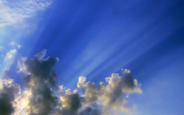 HD PC desktop wallpaper showcasing a vibrant blue sky with sun rays streaming through scattered clouds in a natural setting.