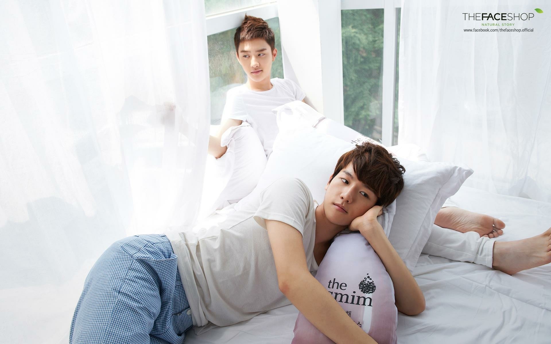 A serene HD desktop wallpaper featuring two members of EXO relaxing in soft, white surroundings, conveying a tranquil and cozy atmosphere.