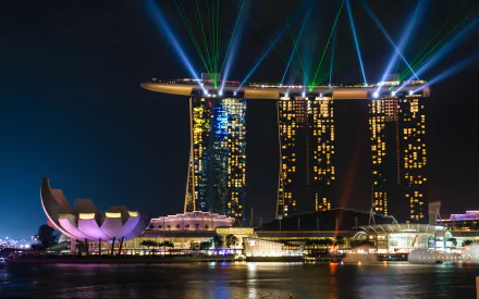 Night view of Singapore’s Marina Bay Sands with vibrant laser lights illuminating the iconic man-made building against the dark sky, captured in HD for a desktop wallpaper.