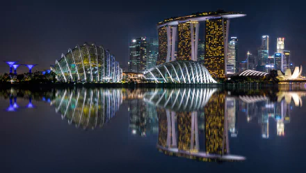 Nighttime reflection of Marina Bay Sands and surrounding illuminated buildings in Singapore, captured in a high-definition wallpaper.