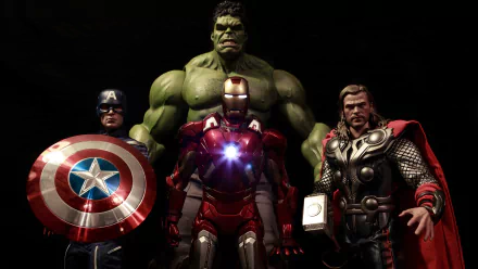 HD desktop wallpaper featuring detailed figurines of Hulk, Thor, Captain America, and Iron Man, inspired by the Avengers. The background is dark, highlighting the vibrant colors and intricate designs of the toys.
