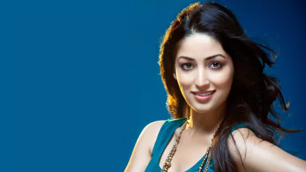 HD desktop wallpaper featuring Bollywood celebrity Yami Gautam smiling against a blue background.