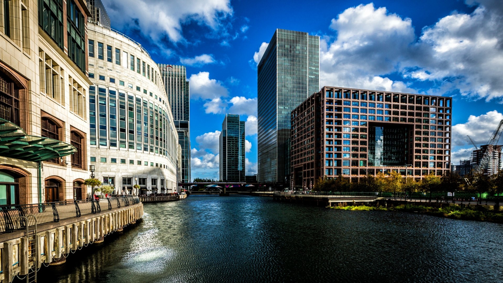 4K Ultra HD desktop wallpaper showcasing London’s modern man-made architecture along a river under a vibrant blue sky with scattered clouds.