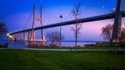 HD desktop wallpaper showcasing the Vasco da Gama Bridge at dusk, featuring illuminated cables and serene waters under a twilight sky.