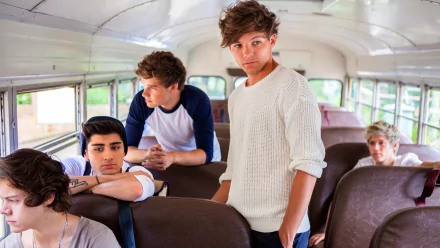 A vibrant HD desktop wallpaper featuring the members of One Direction aboard a bus, capturing a candid moment of camaraderie and music-inspired energy.