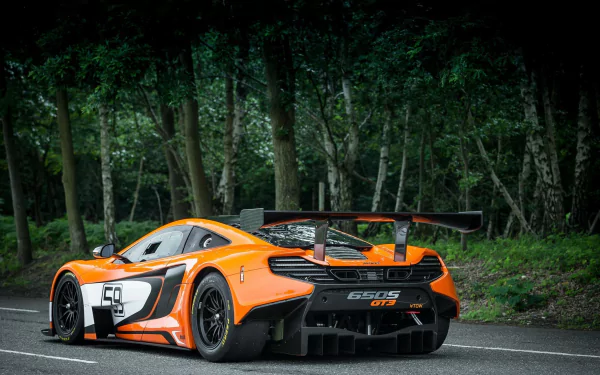 Orange McLaren 650S GT3 supercar, bright orange race vehicle parked on a forest-lined road, rear three-quarter view — HD desktop wallpaper/background.