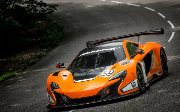 Orange McLaren 650S GT3 supercar racing on a winding road, captured in high definition as a dynamic PC desktop wallpaper.
