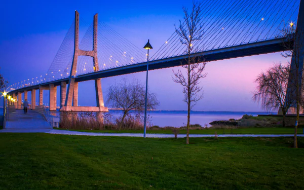 HD desktop wallpaper showcasing the Vasco da Gama Bridge at dusk, featuring illuminated cables and serene waters under a twilight sky.