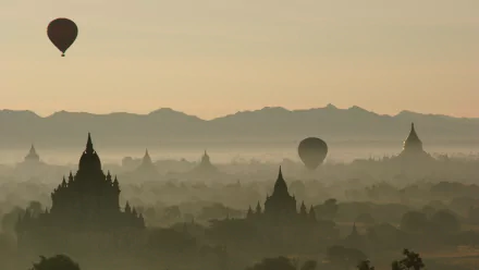 4K Ultra HD PC desktop wallpaper: hot air balloons (air vehicles) drifting over misty pagodas and temple silhouettes at sunrise with distant mountains.